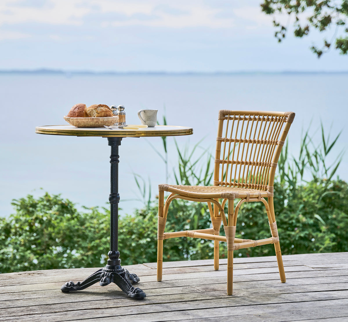 Esta es una imagen de estilo de vida de Elisabeth silla de comedor exterior en natural Aluminium ArtFibre, en una terraza de madera con una mesa de.