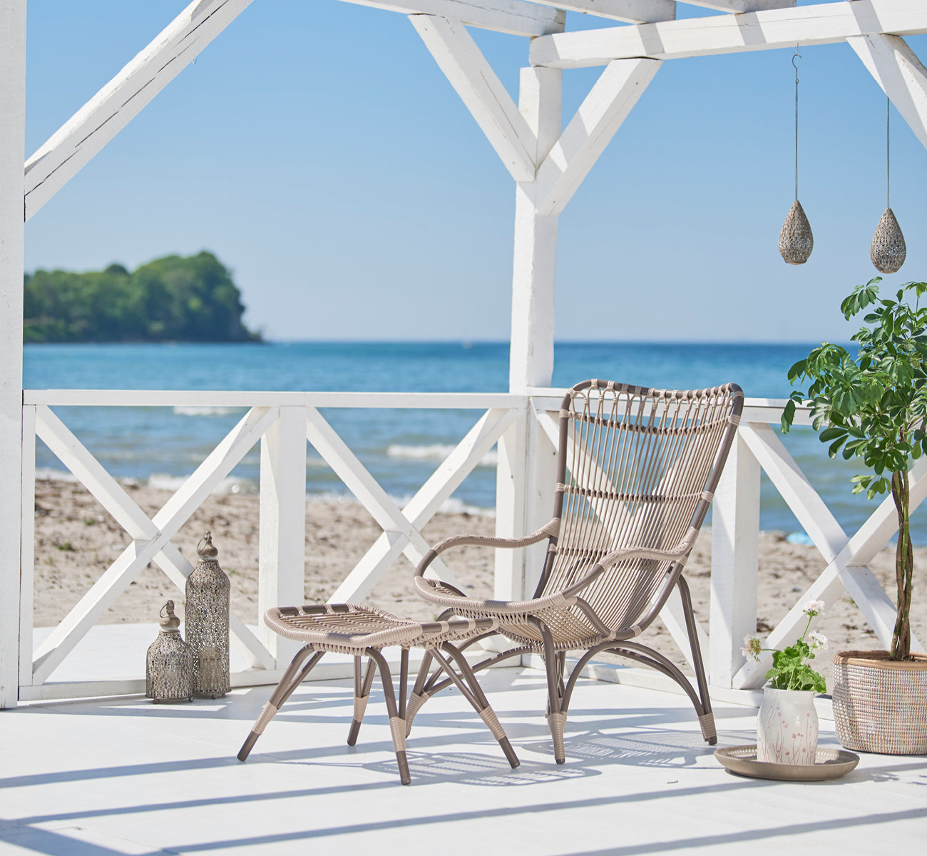 Esta es una imagen de estilo de vida de Monet Exterior Lounge Chair en moccaccino aluminium artfibre. Estilizado en un interior luminoso.