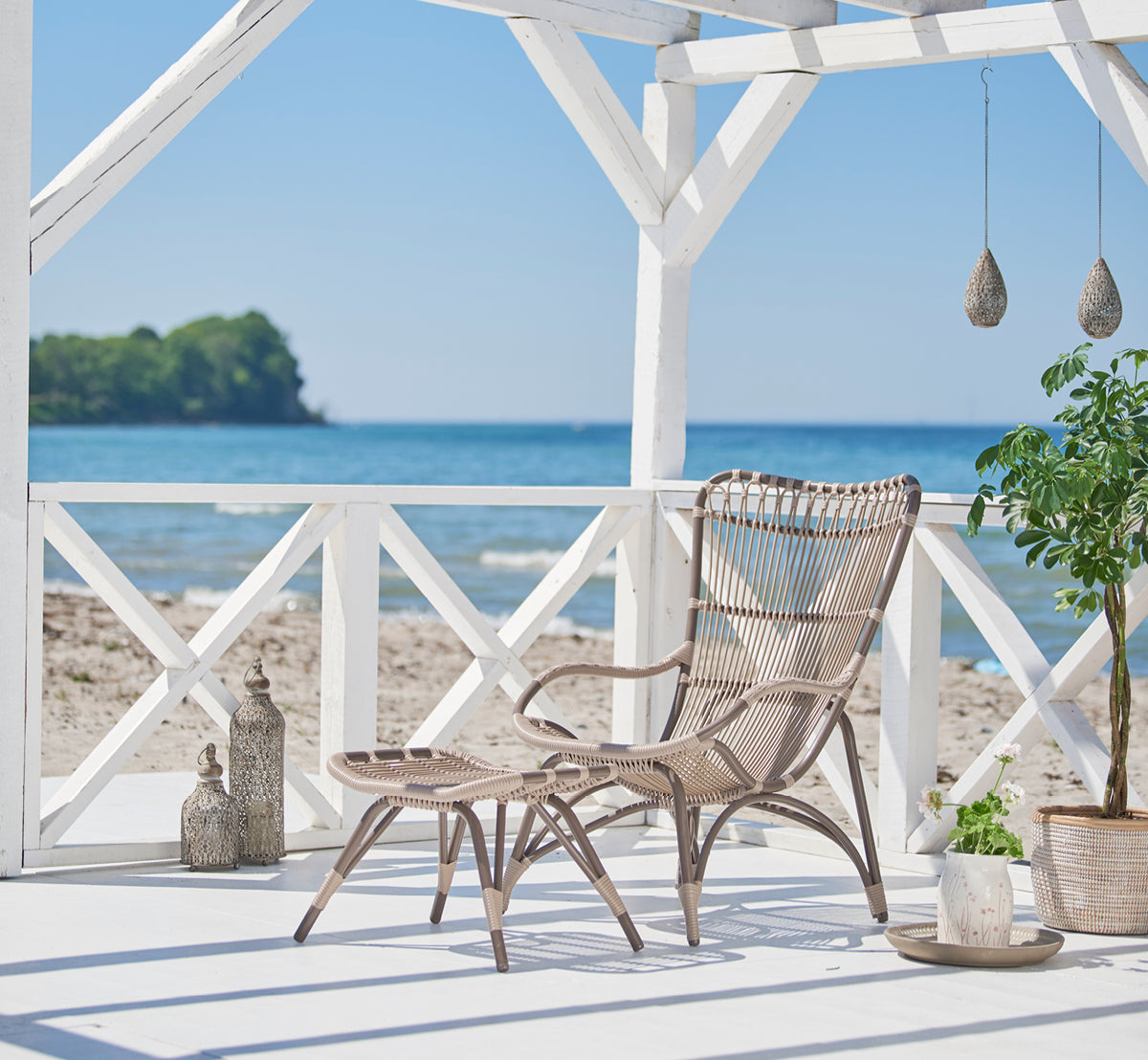 Esta es una imagen de estilo de vida de Monet Exterior Lounge Chair en moccaccino aluminium artfibre. Estilizado en un interior luminoso.