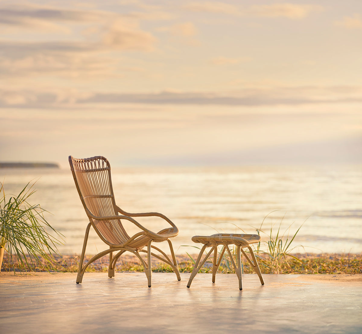 Esta es una imagen de estilo de vida de Monet Exterior Footstool i antique aluminium artfibre. Con sillón lounge en la terraza de un pabellón de playa.