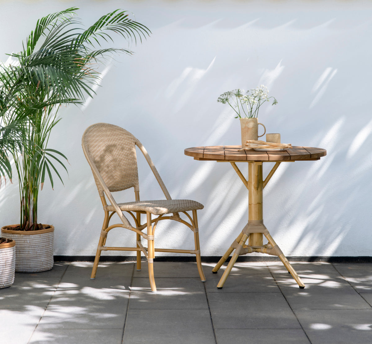 Esta es una imagen de estilo de vida de Nicole Cáfe Table | Teak Ø80 cm en natural aluminium artfibre. Estilizado en un interior luminoso.