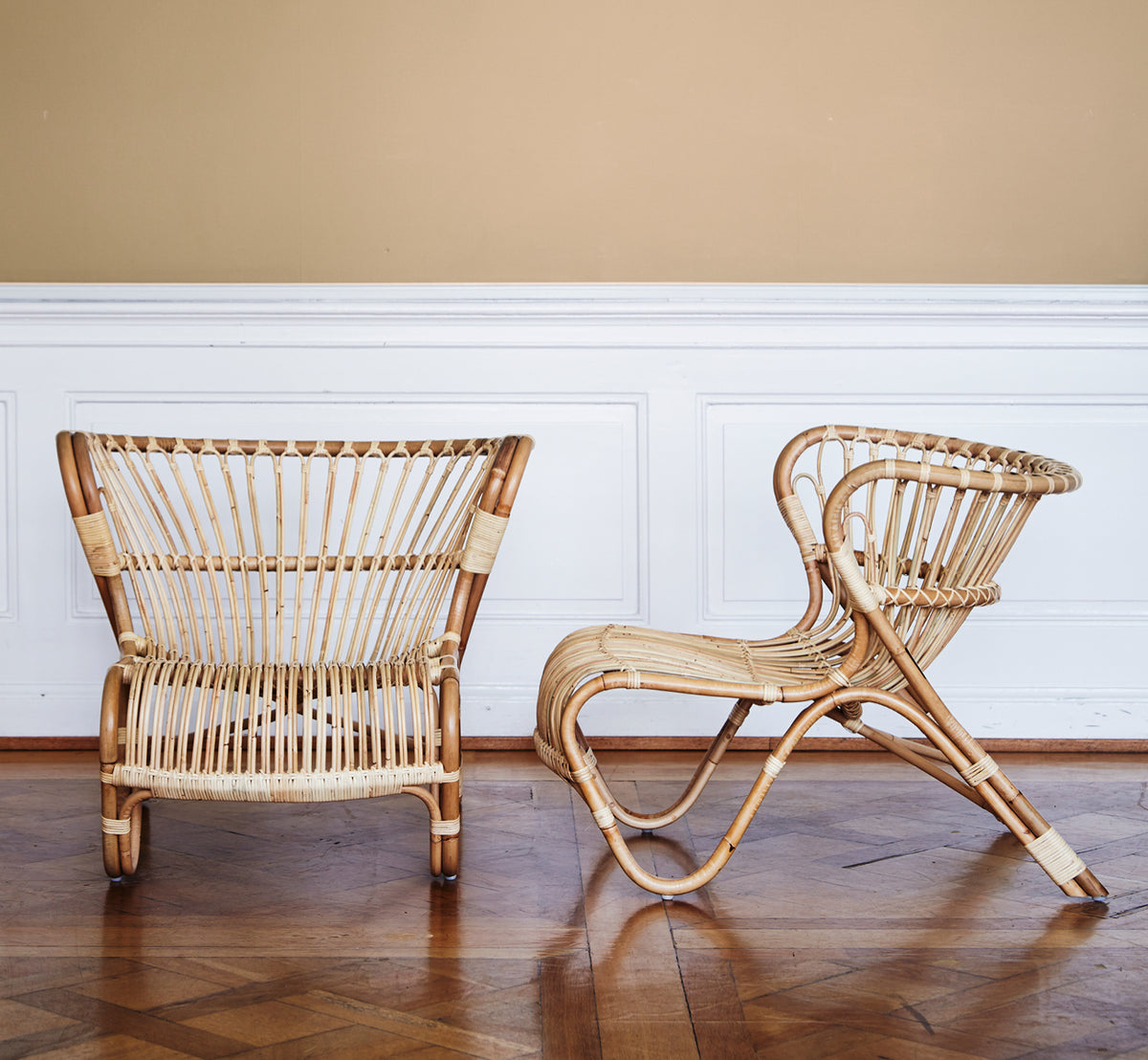 Esta es una imagen de estilo de vida de Fox sillón lounge en polished Natural Rattan, en un interior cálido con lambrisado ocre y parqué oscuro en.