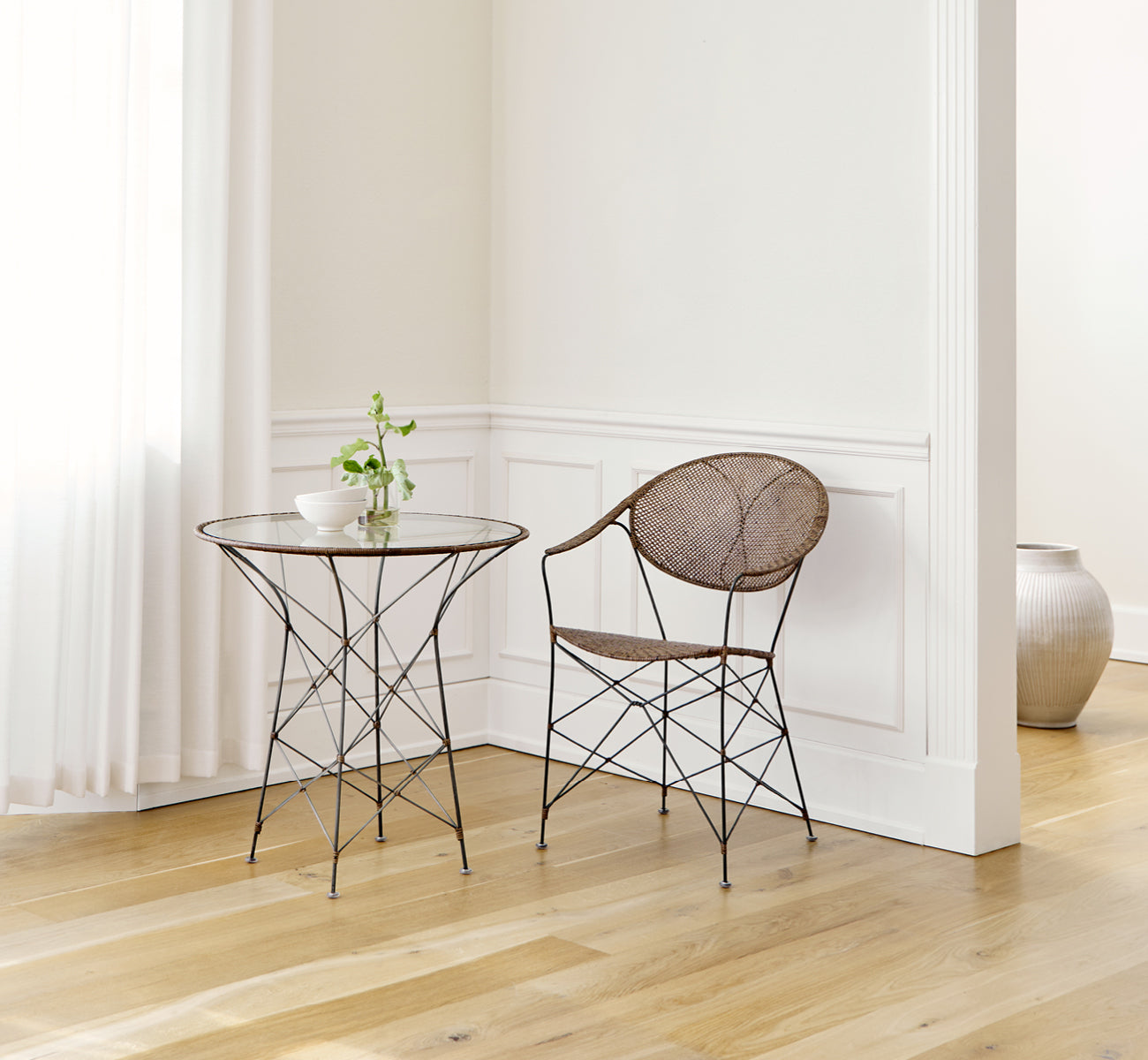 Esta es una imagen de estilo de vida de Funky silla de comedor en hazelnut rattan iron frame, en un interior luminoso con paredes de paneles blancos.