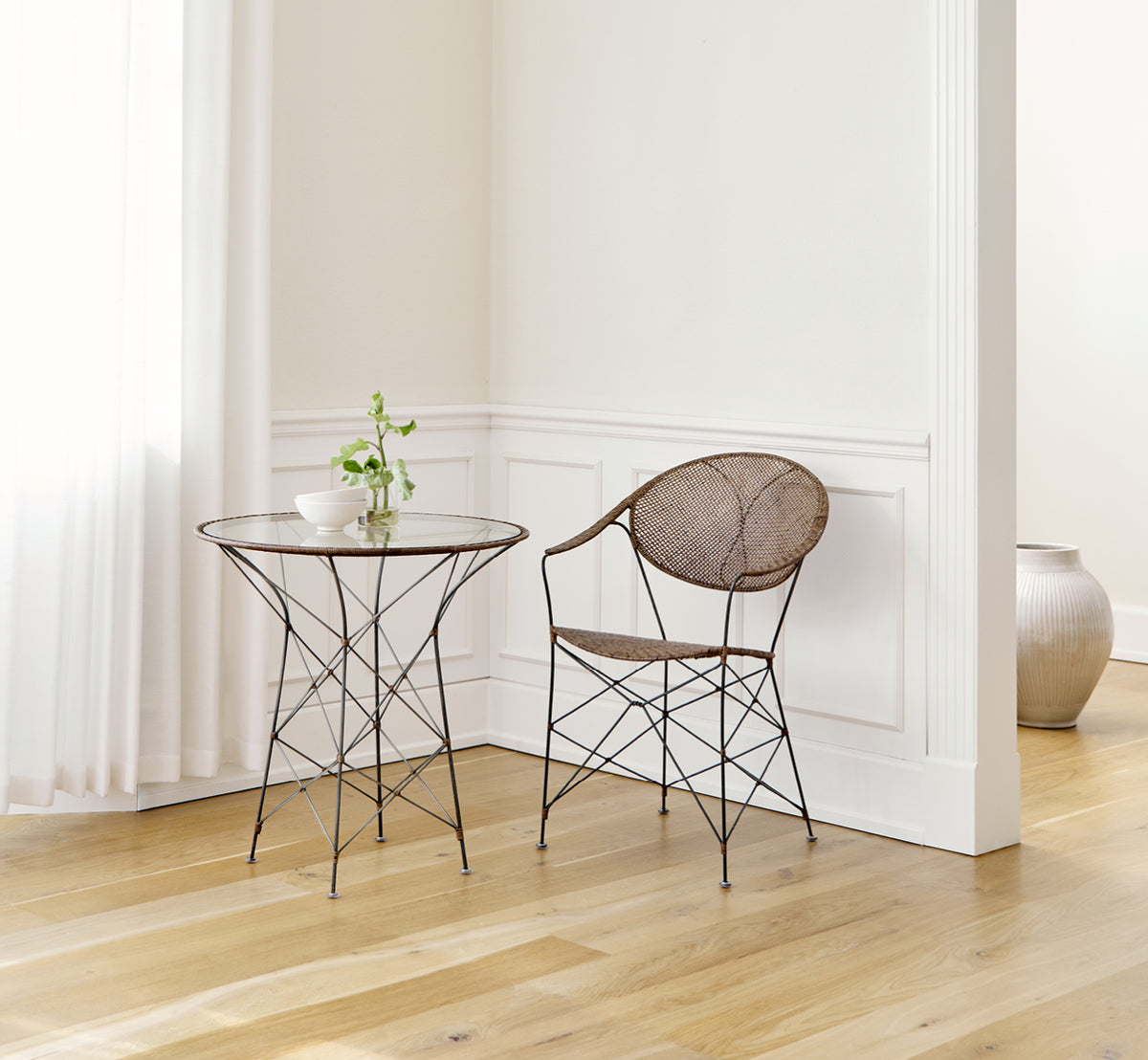 Esta es una imagen de estilo de vida de Funky silla de comedor en hazelnut rattan iron frame, en un interior luminoso con paredes de paneles blancos.