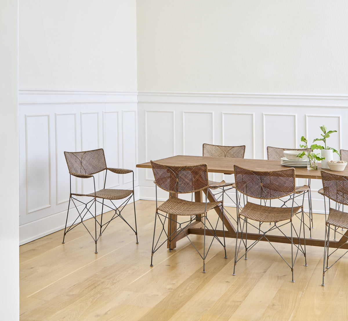 Esta es una imagen de estilo de vida de Rap silla de comedor en hazelnut rattan iron frame, en un interior luminoso con paredes de paneles blancos y.