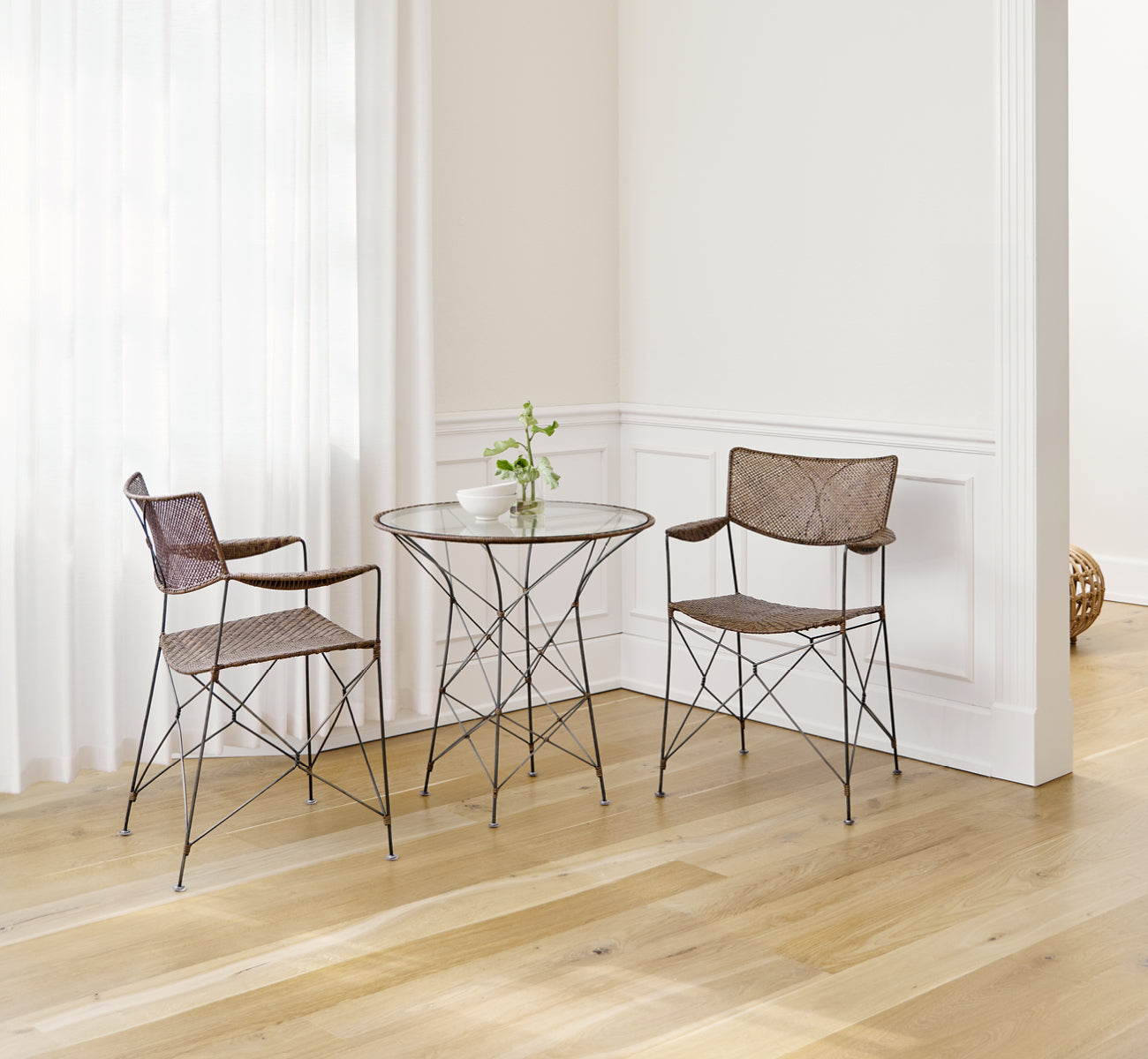 Esta es una imagen de estilo de vida de Rap silla de comedor en hazelnut rattan iron frame, en un interior luminoso con paredes de paneles blancos y.