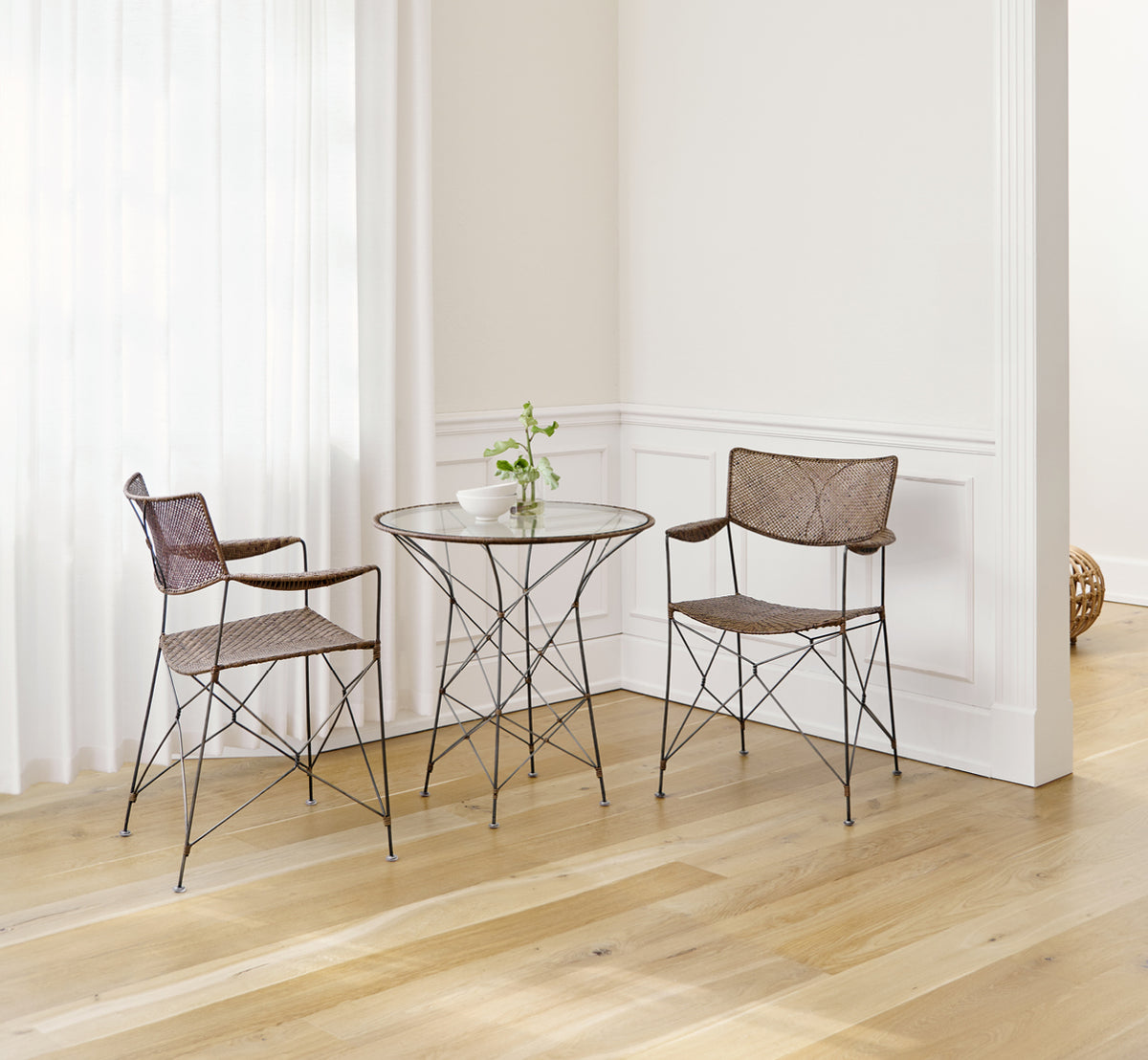 Esta es una imagen de estilo de vida de Rap silla de comedor en hazelnut rattan iron frame, en un interior luminoso con paredes de paneles blancos y.