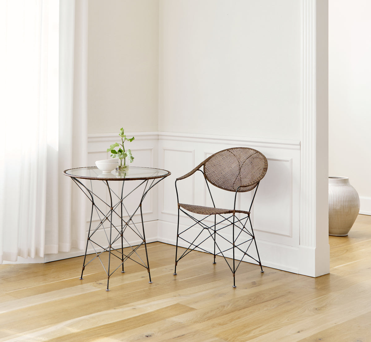 Esta es una imagen de estilo de vida de Funky silla de comedor en hazelnut rattan iron frame, en un interior luminoso con paredes de paneles blancos.