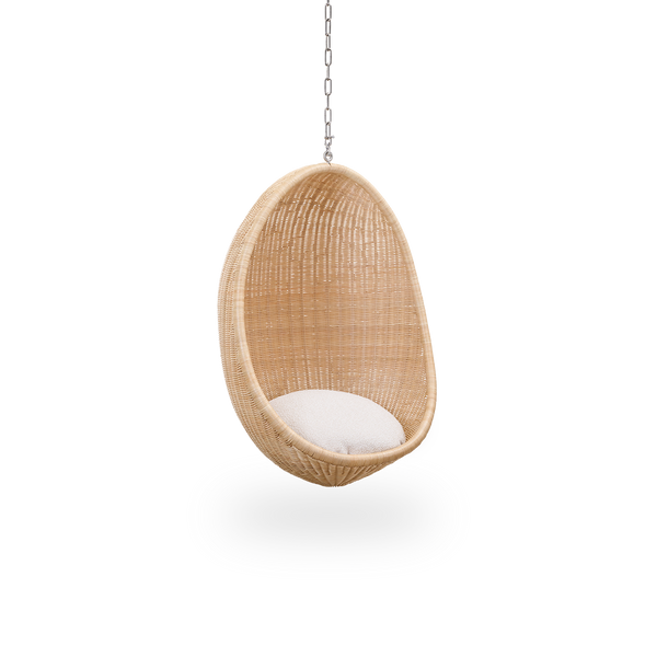 Vista lateral del Hanging Egg Junior, la versión infantil de la icónica silla colgante diseñada por Nanna y Jørgen Ditzel. La silla colgante redonda está completamente tejida con ratán indonesio de alta calidad y cuelga de una cadena metálica.